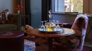 Een kamer met een ronde houten tafel in het midden, een groene bank en een stoel met een gestreept kussen.