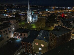 A night view of a cityscape with a prominent church spire, surrounding buildings, and a river. - Bell Hill Apartments (Dunedin)