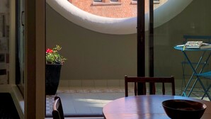 Een moderne kamer met een groot raam, een houten tafel, een stoel en een pot met een plant.