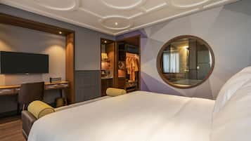 Habitación de hotel con una cama grande, un escritorio con una silla, un televisor y un armario.