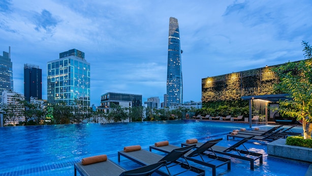 A rooftop pool with lounge chairs and a city skyline in the background.