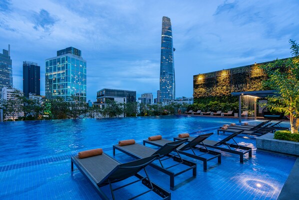 Una piscina al aire libre, sombrillas, sillones reclinables de piscina