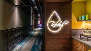 A hallway with a neon sign reading "Pantry Refresh" and a counter with colorful containers.