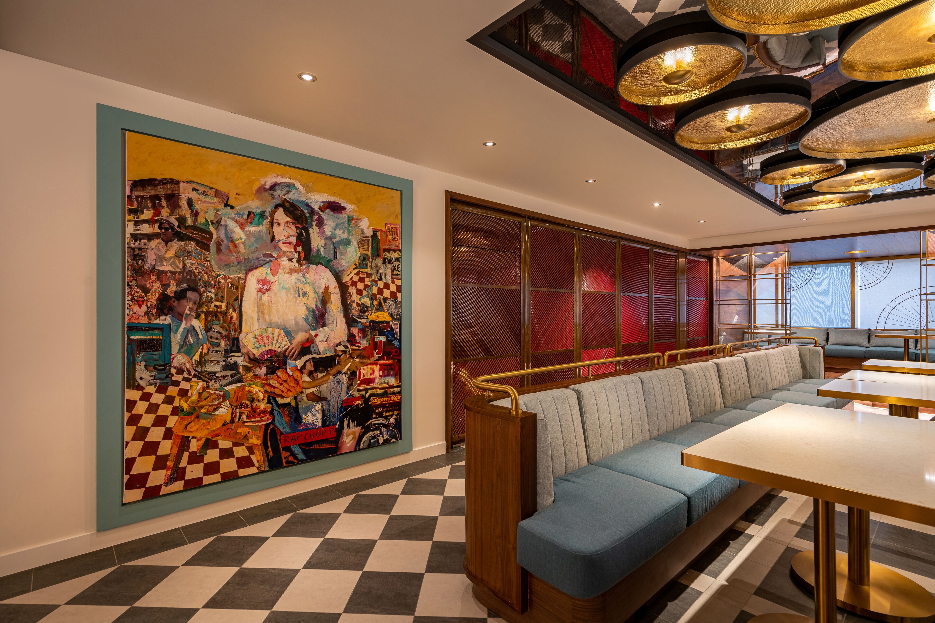 Un restaurante con suelo de cuadros, un mural grande y colorido, un largo banco azul y un diseño moderno del techo.