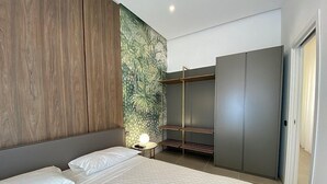 A modern bedroom with a large bed, a wardrobe, and a wall with a tropical mural. - Appartamento Anice B: A welcoming apartment situated in a central location, at a short distance from the main tourist attractions of the city, with Free WI-FI. (Trapani)