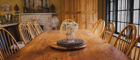 A wooden dining table with a vase of flowers in the center, surrounded by wooden chairs.