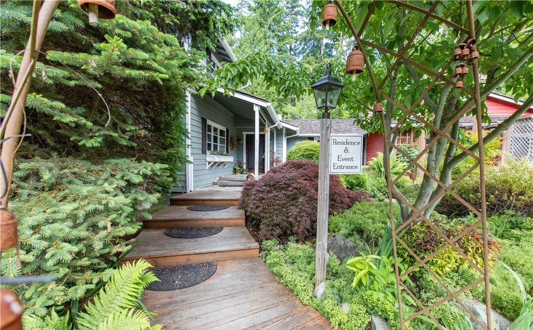 A wooden pathway leading to a house with a sign reading "Residence & Event Entrance."