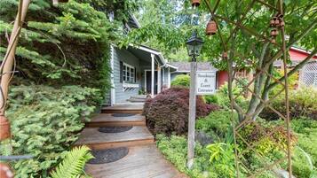 A wooden pathway leading to a house with a sign reading "Residence & Event Entrance."