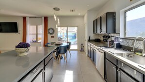 A modern kitchen with a central island, a dining area with chairs, and a view of the outdoors. - Family Home w/ Community Perks in Peoria (Peoria)