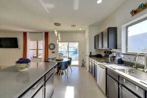 A modern kitchen with a central island, a dining area with chairs, and a view of the outdoors. - Family Home w/ Community Perks in Peoria (Peoria)