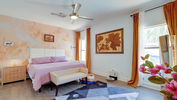 A bedroom with a bed, bedside table, nightstand, ceiling fan, window with curtains, and a wall-mounted artwork. - Family Home w/ Community Perks in Peoria (Peoria)