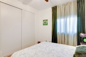 A bedroom with a bed, a wardrobe, a wall-mounted picture, and a window with curtains. - Family Home w/ Community Perks in Peoria (Peoria)