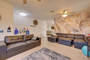 A modern living room with a leather sofa, a patterned rug, and a ceiling fan. - Family Home w/ Community Perks in Peoria (Peoria)