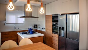 Una cocina moderna con una isla central, electrodomésticos de acero inoxidable e iluminación colgante.