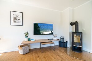 A modern living room with a wooden bench, a TV, a fireplace, and a framed picture on the wall.