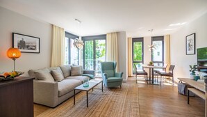 Uma sala de estar moderna com sofá, poltrona, mesa de centro e área de jantar.