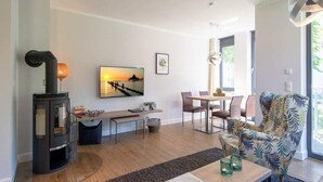 Ein modernes Wohnzimmer mit Kamin, Essbereich und großem Fenster.