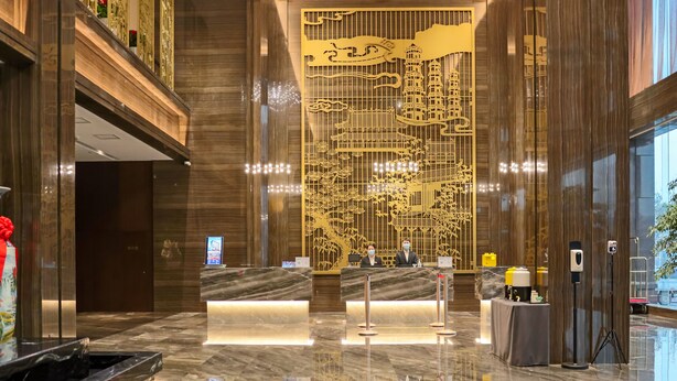 A lobby with a reception desk, marble flooring, and a decorative wall with intricate designs. - YUN-RAY PHOENIX HOTEL (Jinzhong)