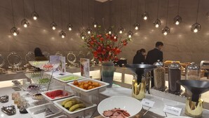 A buffet with various food items, including fruits, vegetables, and meats, arranged on a marble counter. - YUN-RAY PHOENIX HOTEL (Jinzhong)