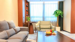 A modern living room with a sofa, armchair, coffee table, and a potted plant. - YUN-RAY PHOENIX HOTEL (Jinzhong)