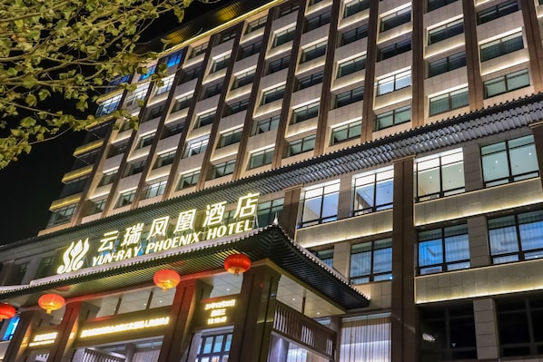 A hotel with a traditional architectural style, featuring a prominent sign with Chinese characters and a modern facade.