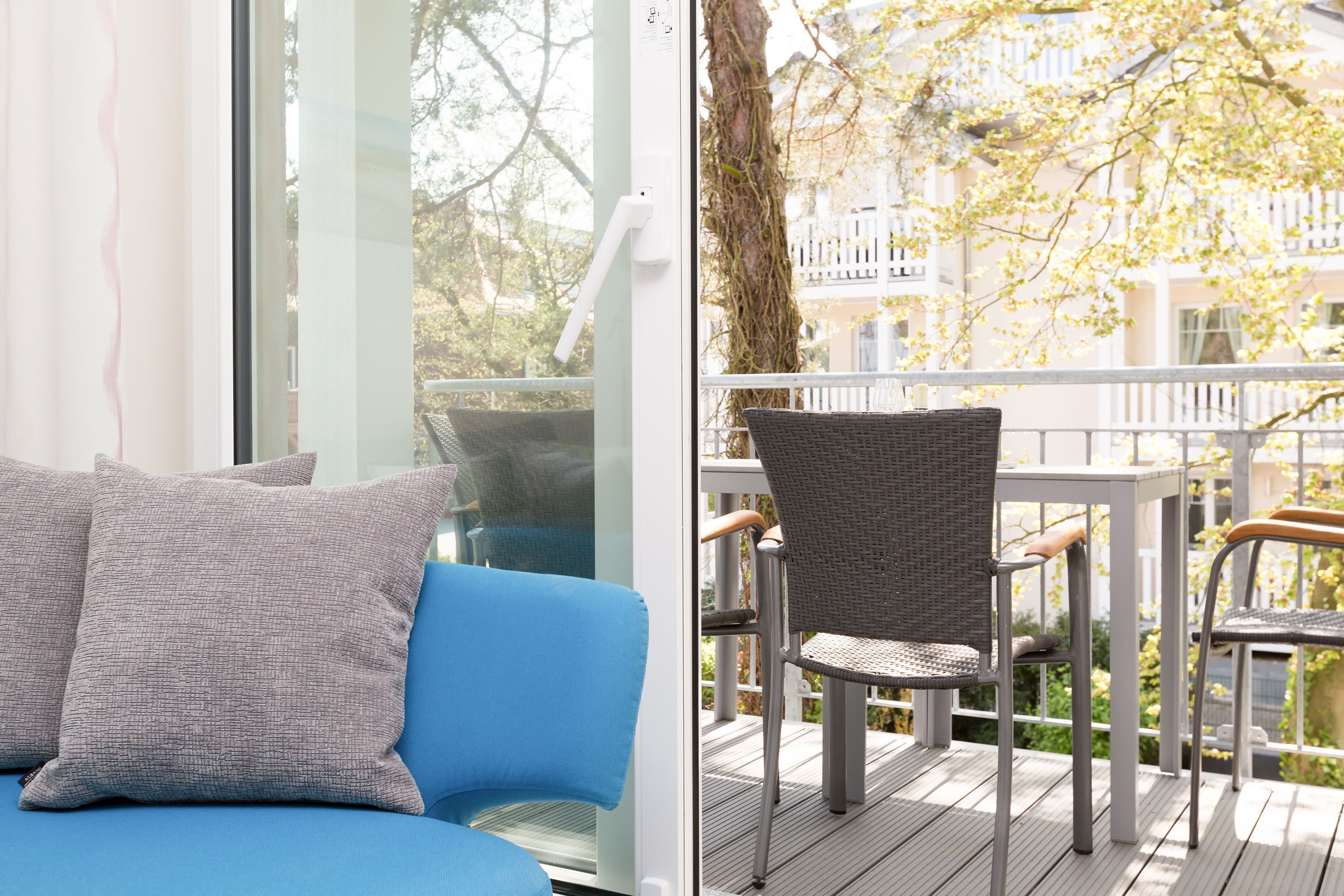 A balcony with wicker chairs and a blue sofa with grey cushions.