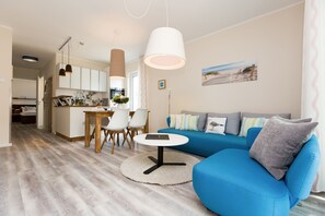 Un salon moderne avec un canapé bleu, une table basse ronde et un coin repas comprenant des chaises et une table.