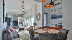 A modern living room with a sofa, a dining table with chairs, and a kitchen area in the background. - Beaumont Cottages 2 by CTHA (Cape Town)