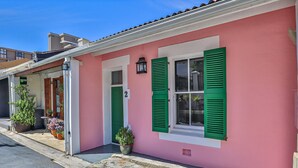 A pink building with green shutters, a number '2' sign, and potted plants outside. - Beaumont Cottages 2 by CTHA (Cape Town)