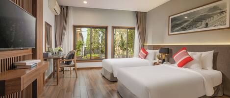 A hotel room with two beds, a desk with a chair, a TV, and a large window with curtains.