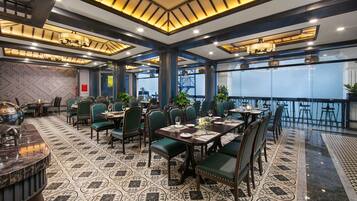 A restaurant with a patterned floor, green upholstered chairs, and a bar area.