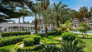 A resort with a pool, palm trees, and a covered walkway. - Utopia Resort & Residence (Alanya)