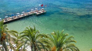 A pier extending into clear blue water with lounge chairs and umbrellas. - Utopia Resort & Residence (Alanya)