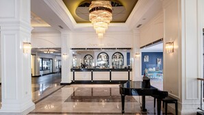 A grand lobby with a piano, a bar area, and a chandelier. - Utopia Resort & Residence (Alanya)