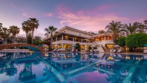 A hotel with a large swimming pool, palm trees, and a sunset sky. - Utopia Resort & Residence (Alanya)