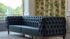A dark green tufted sofa with wooden legs in a modern room with a bamboo wall and large windows. - Sunrise Hotel (Sinop)