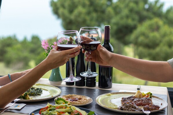 Una mesa de comedor con platos de comida, copas de vino y una botella de vino.