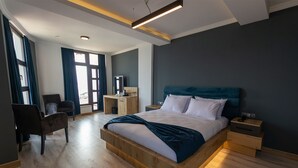 A modern hotel room with a large bed, wooden headboard, and a desk with a chair. - Sunrise Hotel (Sinop)
