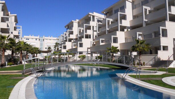 Um prédio de apartamentos moderno com piscina e uma ponte.