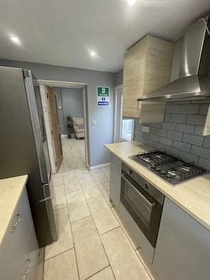 Fully equipped kitchen with a refrigerator, gas stove, and range hood, offering a clean and minimalist design.