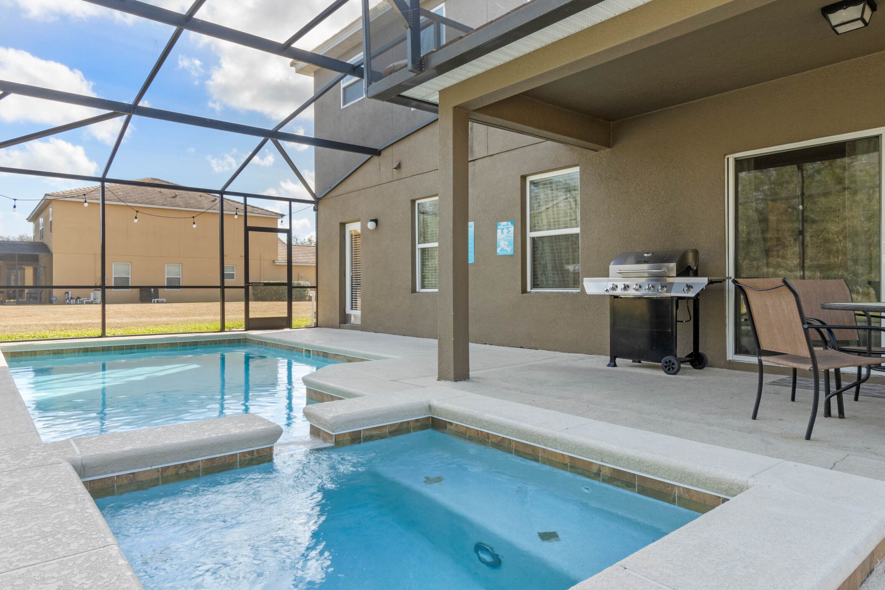 Une piscine extérieure avec un patio couvert, un barbecue et des espaces de détente en plein air.