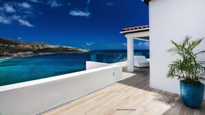 A modern outdoor terrace with a clear view of the ocean and a distant coastline. - Villa Amalia – 6-Bedroom Luxury Oceanview Villa with Pool, Gym & Full Staff in St. Maarten (Philipsburg)