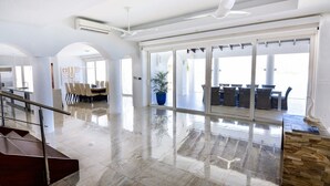 A spacious hotel lobby with a marble floor, a staircase, and a seating area with tables and chairs. - Villa Amalia – 6-Bedroom Luxury Oceanview Villa with Pool, Gym & Full Staff in St. Maarten (Philipsburg)