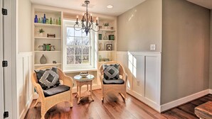 A cozy room with two wicker chairs, a small table, and a bookshelf filled with decorative items. - Morrisonville Manor w/ Fire Pit & Hot Tub! (Lovettsville)