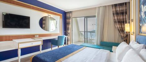 A hotel room with a bed, a desk, a chair, a TV, and a balcony with curtains.