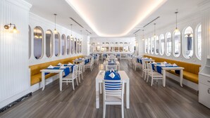 Un restaurante amplio con paredes blancas, asientos acolchados amarillos y varias mesas de comedor.