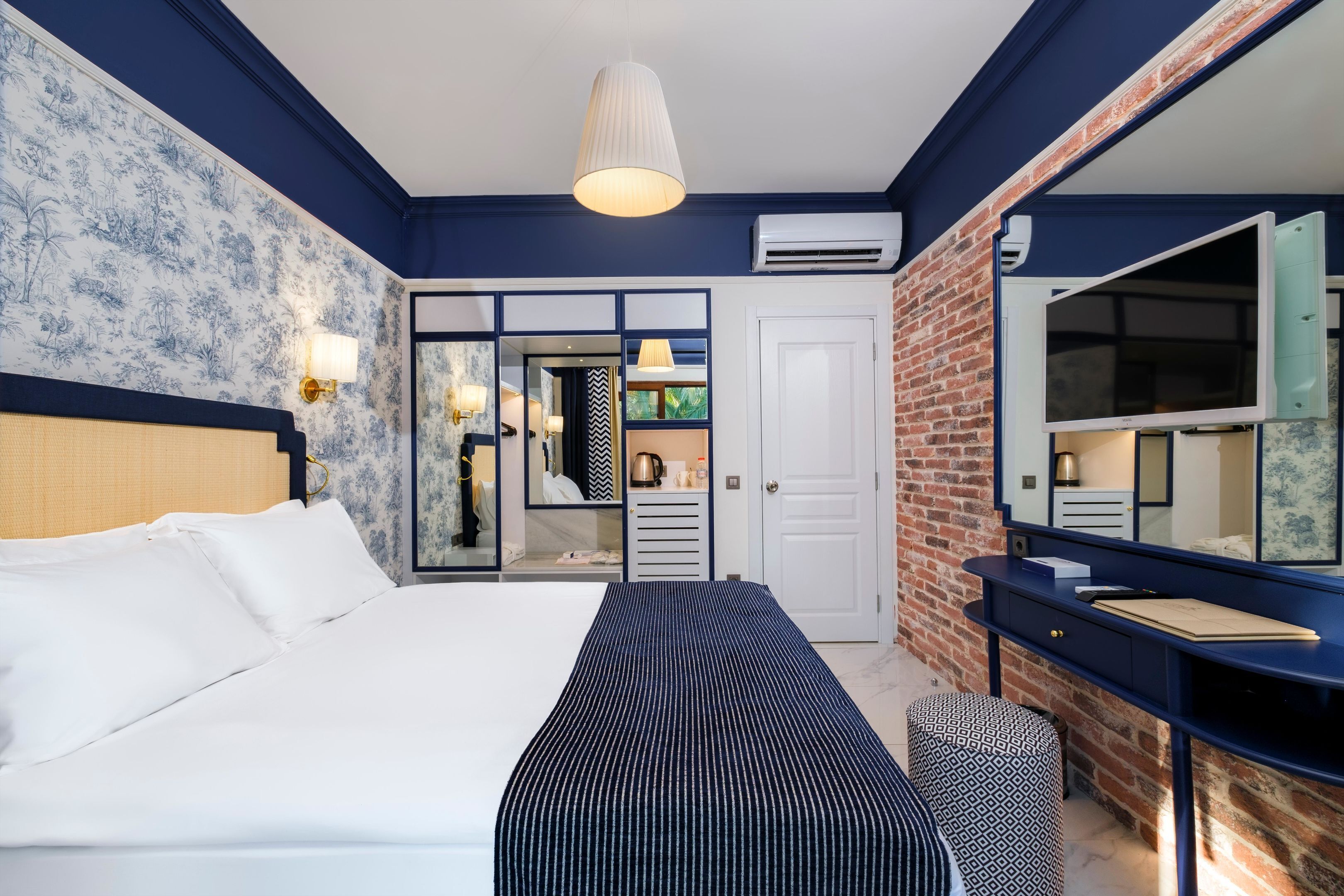 A hotel room with a large bed, a dresser, a mirror, and a wardrobe.