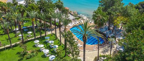 Un resort con piscina, palmeras y vista al mar.