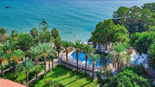Un resort con piscina rodeado de palmeras y vista al mar.
