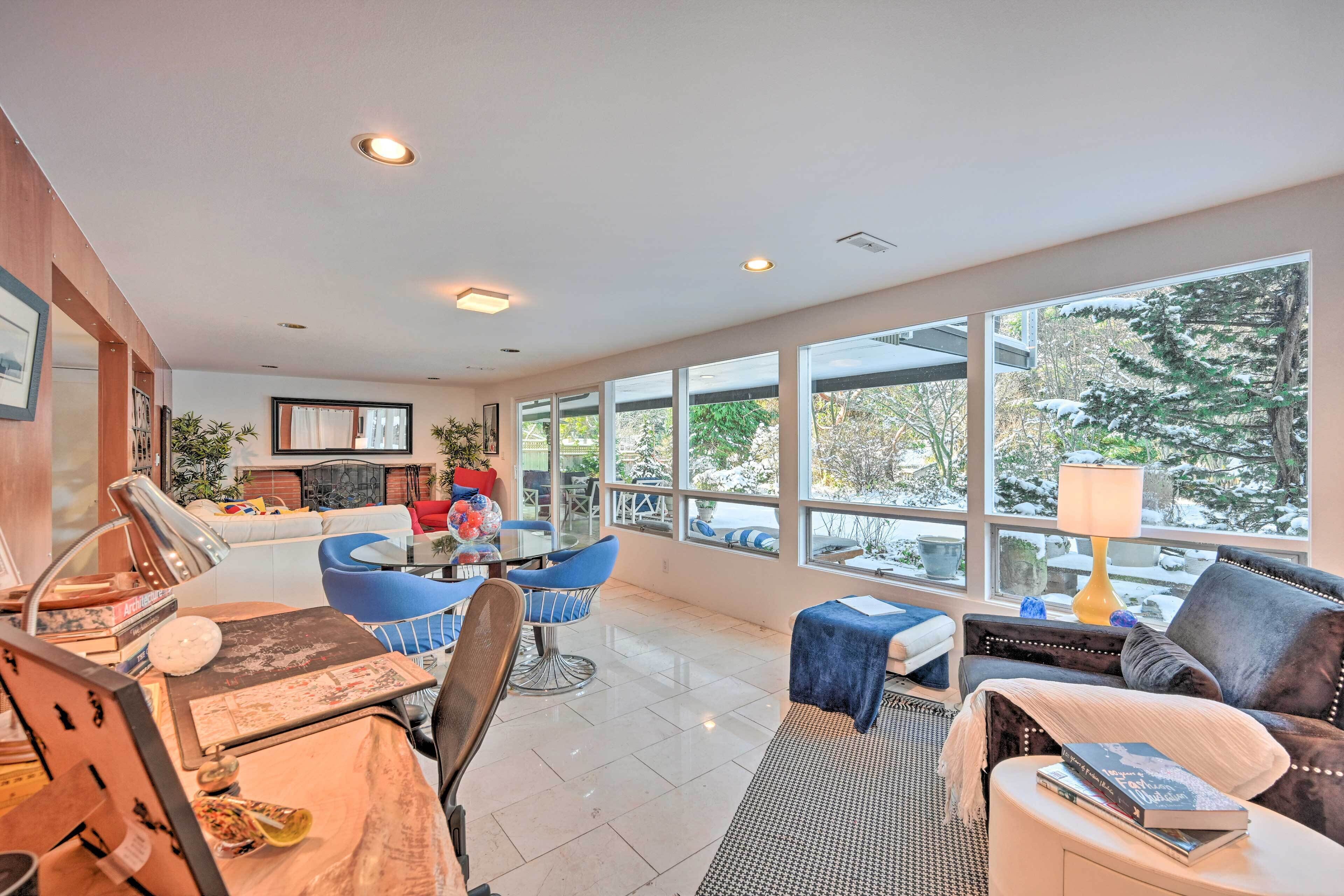 A spacious living room with a fireplace, large windows, and modern furniture.